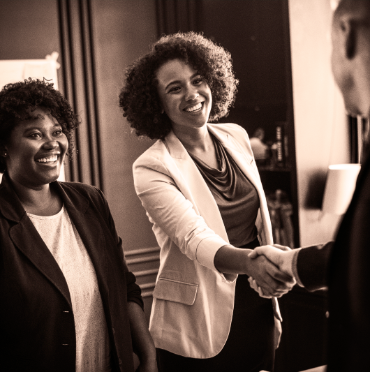 black and white picture of two women shaking hands with a man